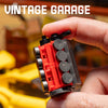 A hand holds a red and black vintage garage building block set with various pieces.