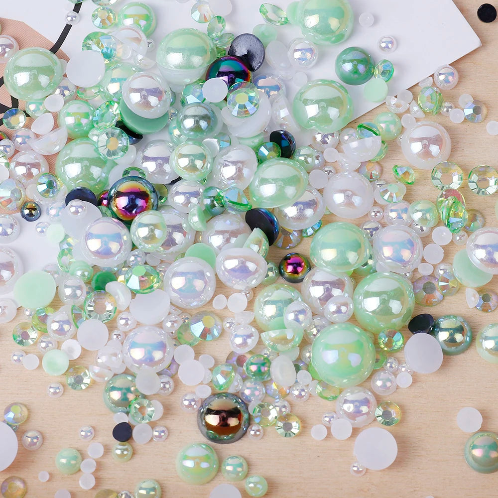 A scatter of mixed resin rhinestone pearls with an AB finish in various shades of green and clear on a wooden surface.