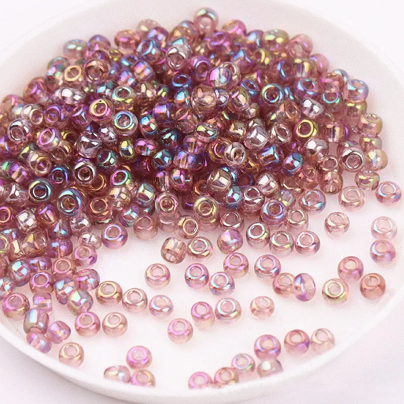 A pile of iridescent purple and pink glass rice beads for DIY jewelry and crafting.