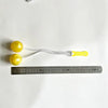 Yellow click clack stress relief fidget balls strung on a white cord placed above a ruler.