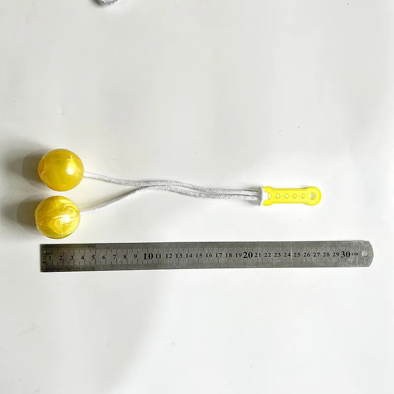 Yellow click clack stress relief fidget balls strung on a white cord placed above a ruler.