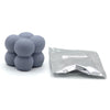 A pile of round gray candle dye chips next to a small plastic bag.