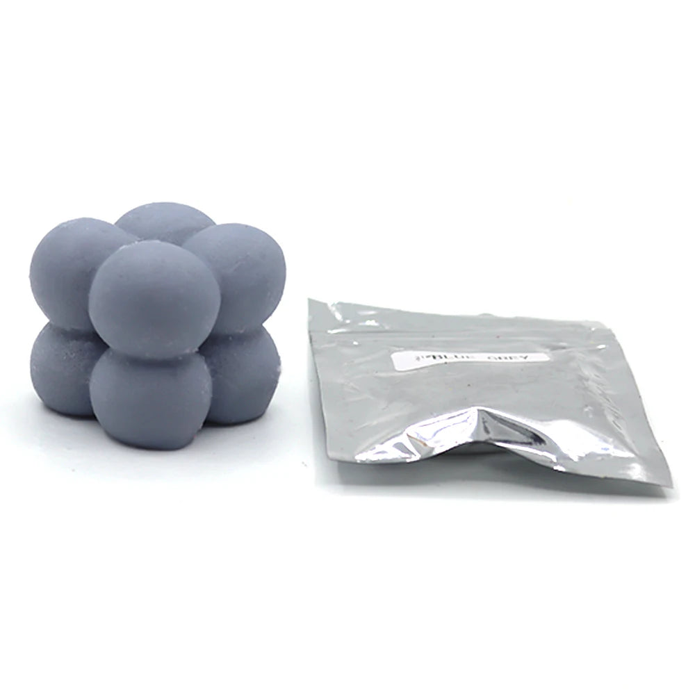 A pile of round gray candle dye chips next to a small plastic bag.