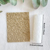A beige clay texture roller is shown next to a white rolled item on a light surface.