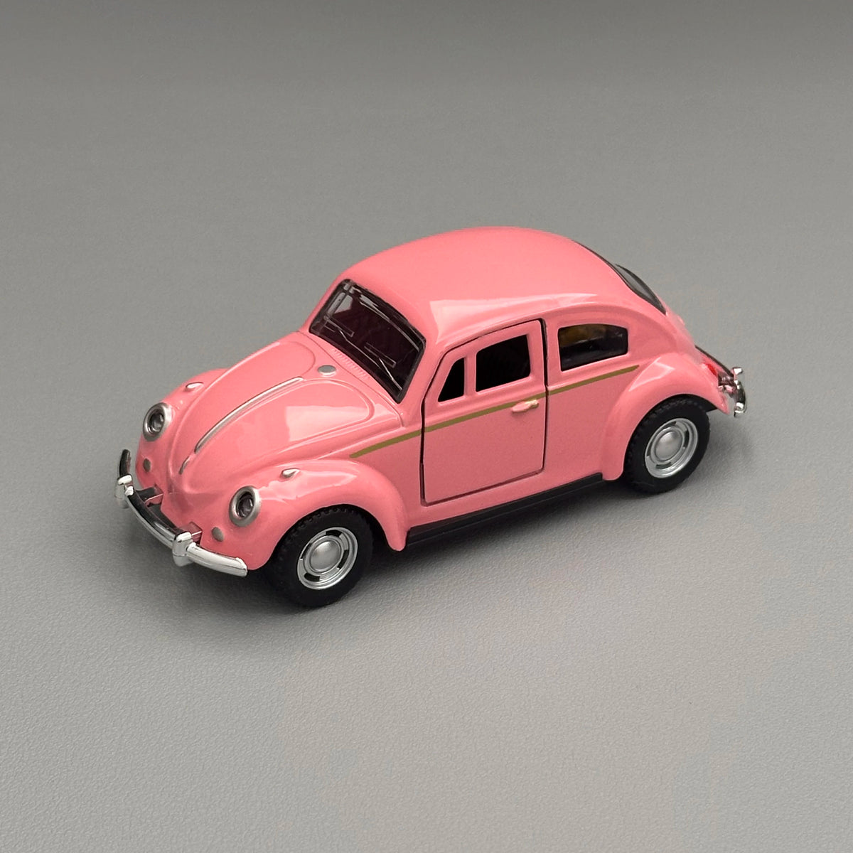 A pink classic retro Beetle diecast model car with a black roof and chrome details.