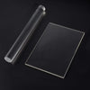 A clear acrylic clay roller and sheet set displayed on a dark surface.