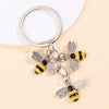 Silver keychain featuring enamel flowers shaped like bees with yellow and black stripes