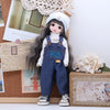A doll dressed in a denim outfit and a white bonnet stands next to a box of flowers.