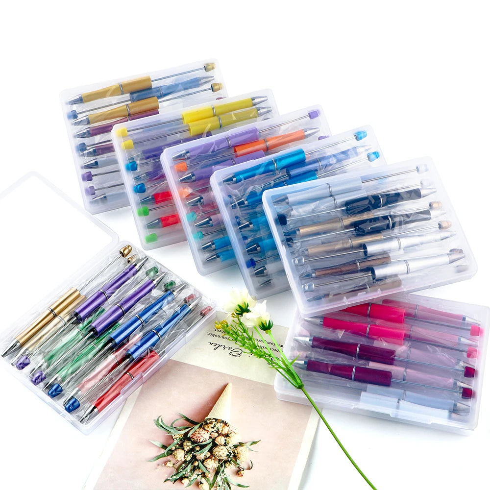 A collection of DIY beaded ballpoint pen kits in clear plastic packaging with various colored pens and accessories.
