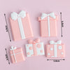 Pink and white rectangular cake toppers shaped like gifts with bows for birthday or baby shower
