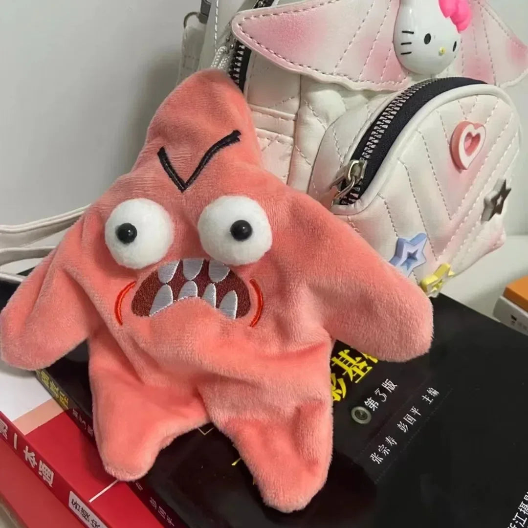 A fluffy pink starfish plush toy with embroidered features resting on a black surface.