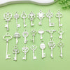 A collection of vintage silver key charms and pendants arranged on a light green surface.