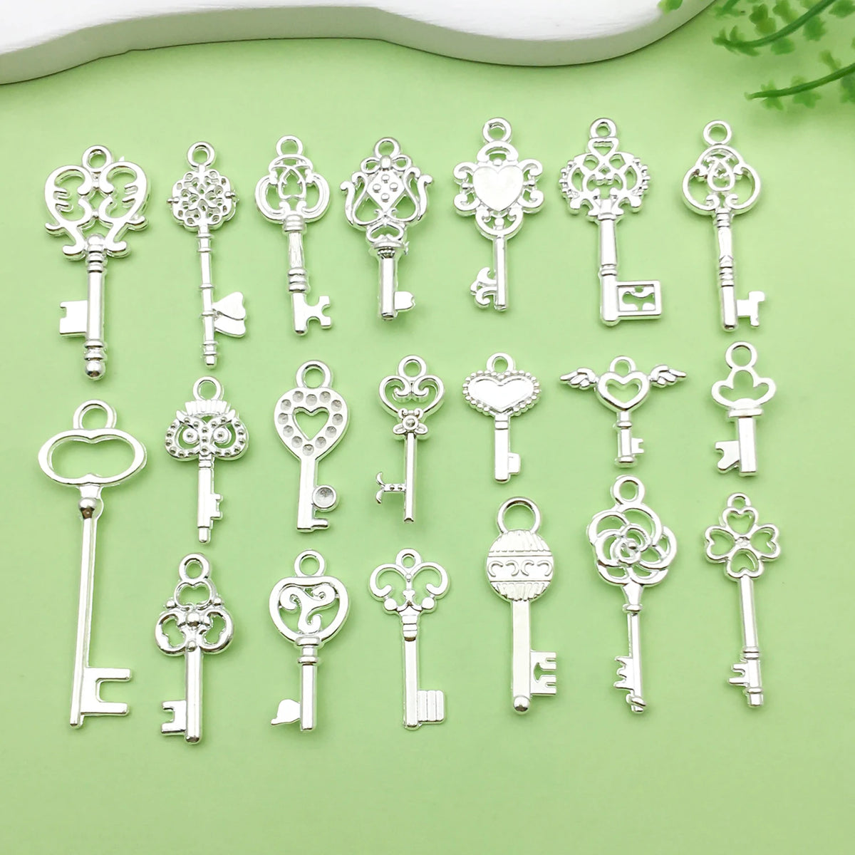 A collection of vintage silver key charms and pendants arranged on a light green surface.
