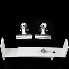 A white wooden bracelet weaving jig with metal clips is displayed against a black background.