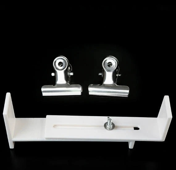 A white wooden bracelet weaving jig with metal clips is displayed against a black background.