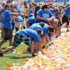 A person is filling a large pile of colorful water balloons for an outdoor summer fun activity.