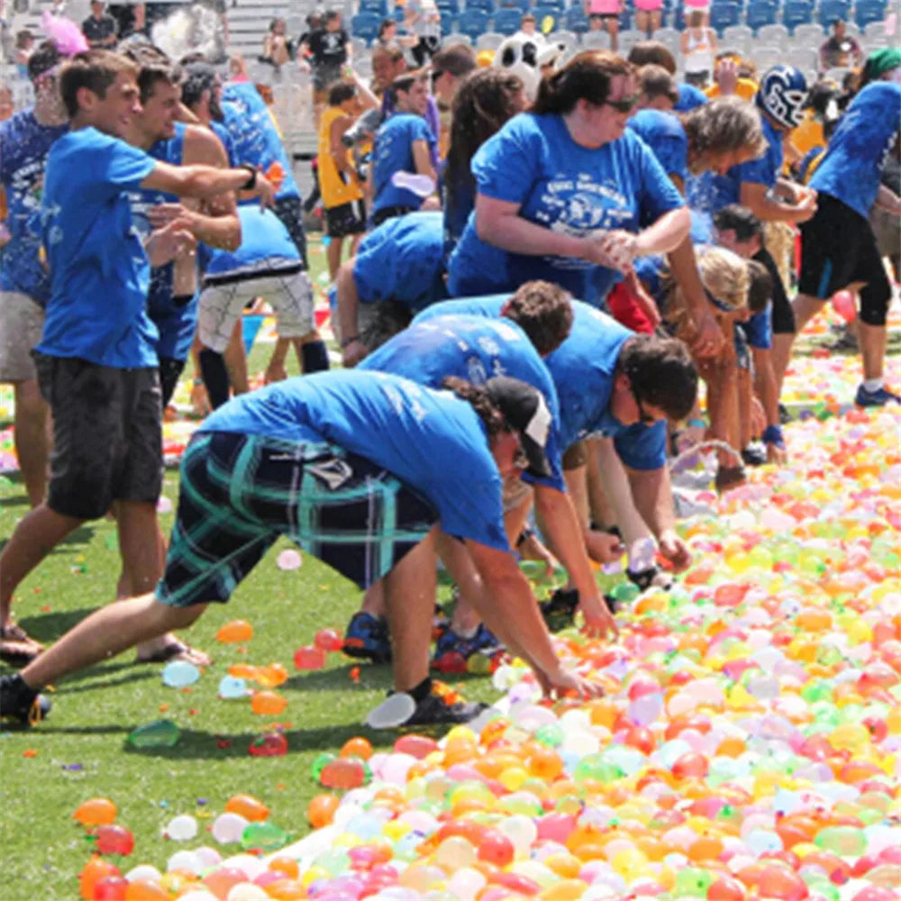 A person is filling a large pile of colorful water balloons for an outdoor summer fun activity.