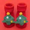 Pair of red baby anti-slip cotton socks with festive green Christmas tree designs