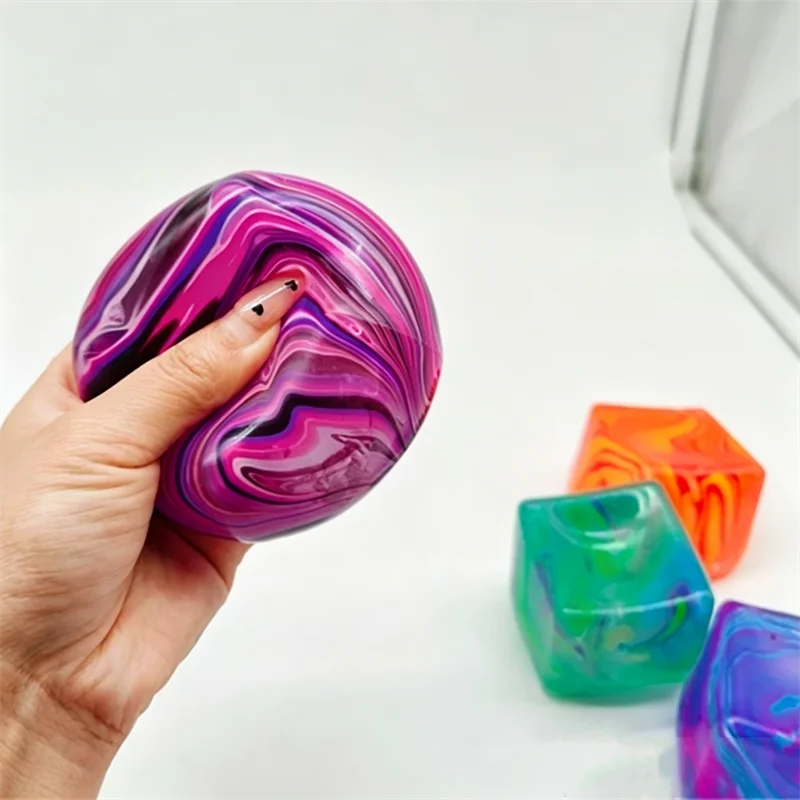 A hand holds a swirling purple and pink cube toy, demonstrating its marbled texture.