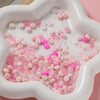 A white dish filled with pink and clear glass spacer beads.