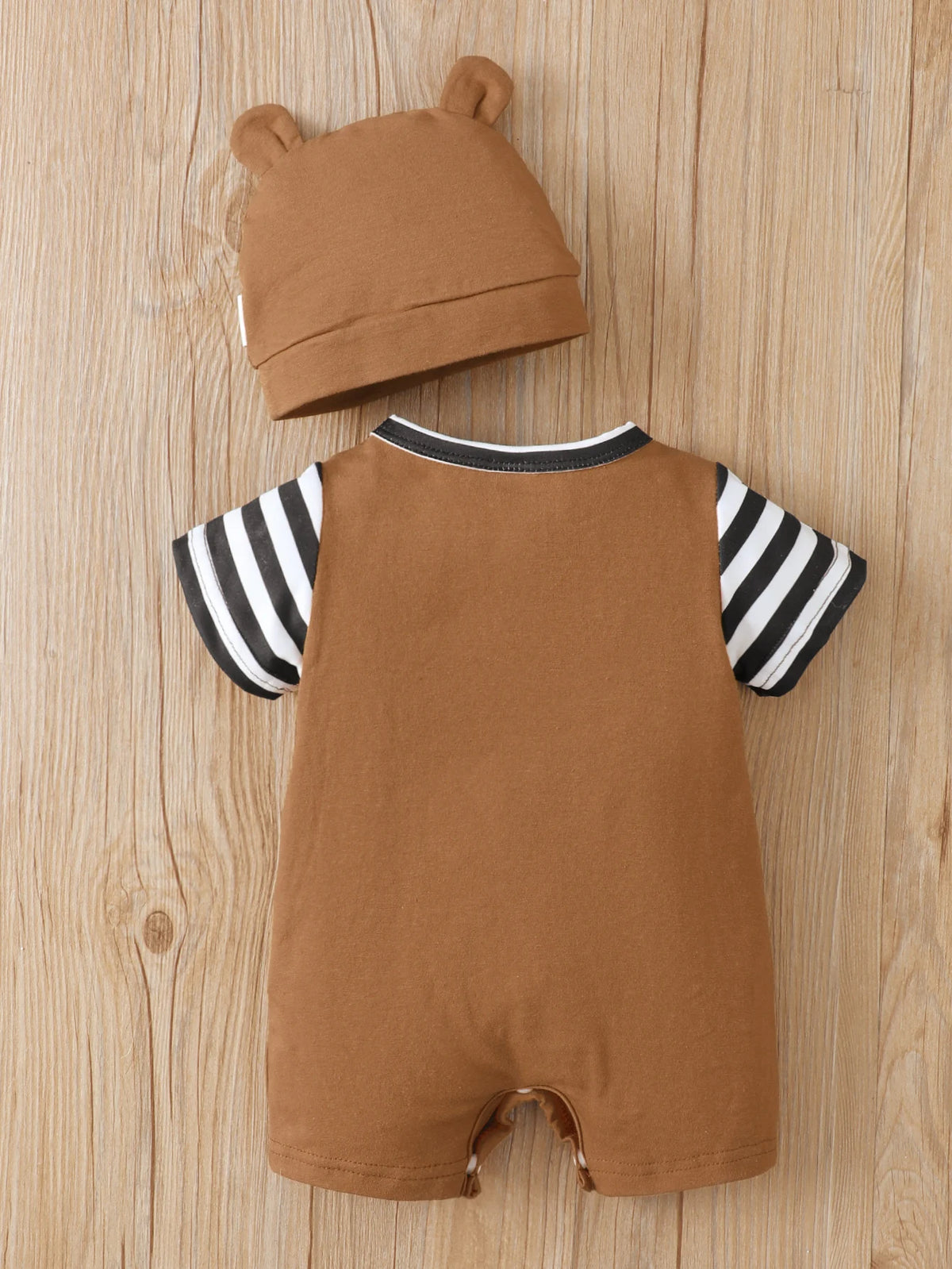 A brown baby romper and matching hat with black and white stripes displayed on a wooden surface.