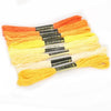 A set of multicolor embroidery floss skeins in orange, yellow, and white with a glitter finish.