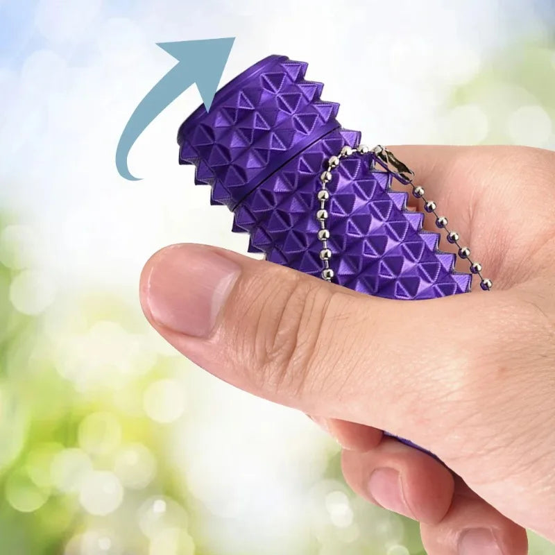 A hand holds a purple spiky fidget key charm designed for stress relief.