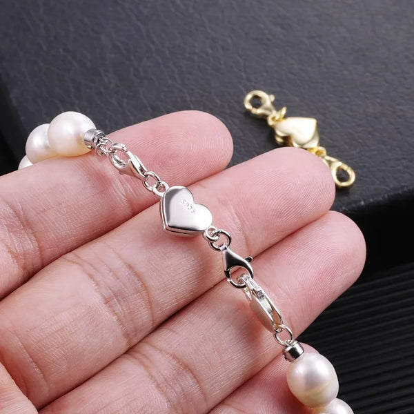 Silver heart-shaped magnetic clasp necklace with pearl beads shown on a hand