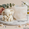 A white silicone elephant mold sits next to a white candle, displayed on a marble surface.