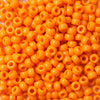 A close-up view of a 100-pack of small, bright orange, round pony beads for jewelry making.