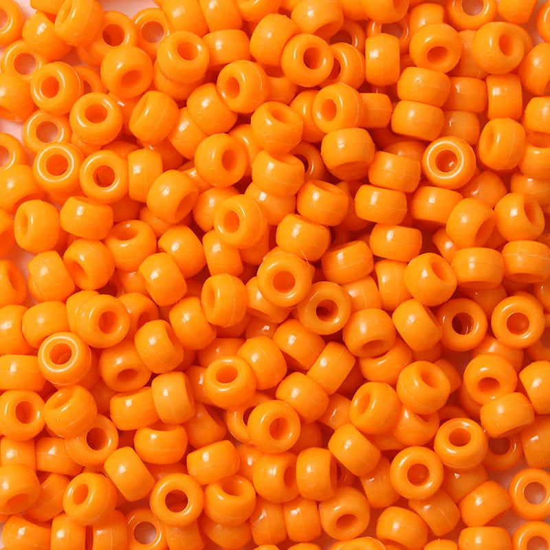 A close-up view of a 100-pack of small, bright orange, round pony beads for jewelry making.
