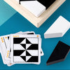 A stack of cards featuring a geometric pattern is placed next to a white block on a light wooden tray.