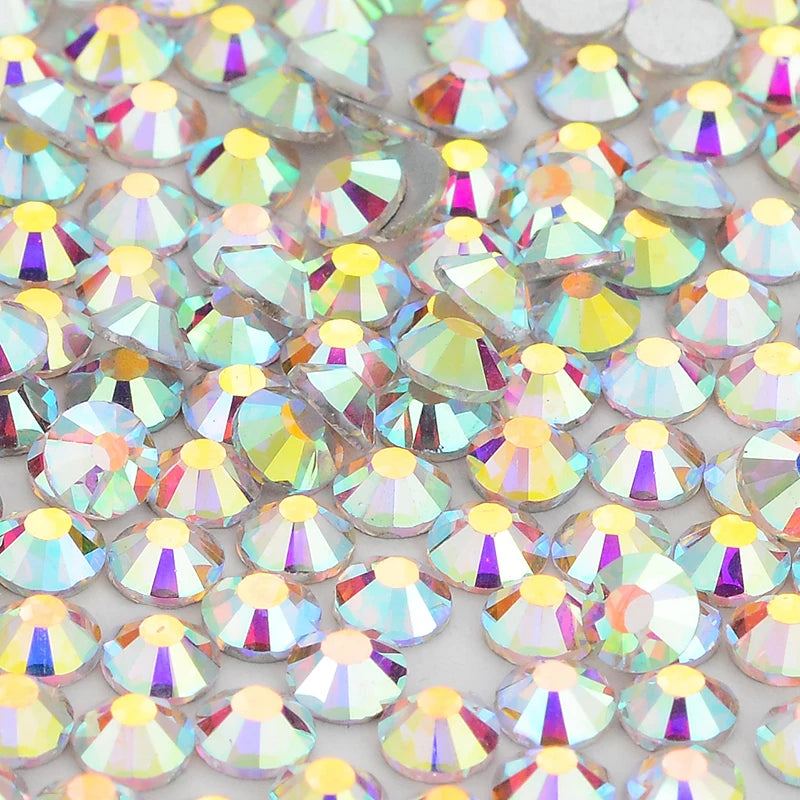 A close-up view of iridescent glass crystal flatback rhinestones in various colors and shapes.