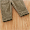 A close-up of olive green baby cotton overalls with ribbed fabric texture lying on a wooden surface.