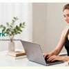 A woman is using a wireless 4D shiatsu neck and shoulder massager while working on a laptop.