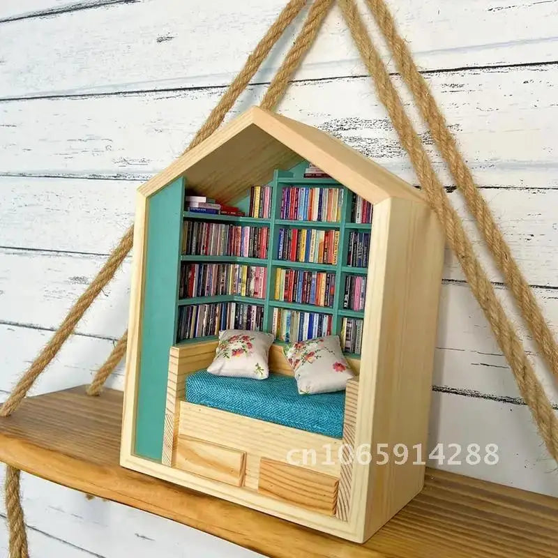A wooden miniature bookshelf decor set with a pitched roof, filled with colorful books, hanging from thick rope.
