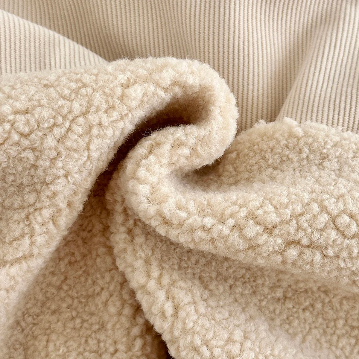 A close-up of a beige fleece-lined winter coat fabric folded and draped.