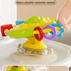 A bright green and yellow cartoon baby rattle toy with a suction cup is shown being played with by a hand.