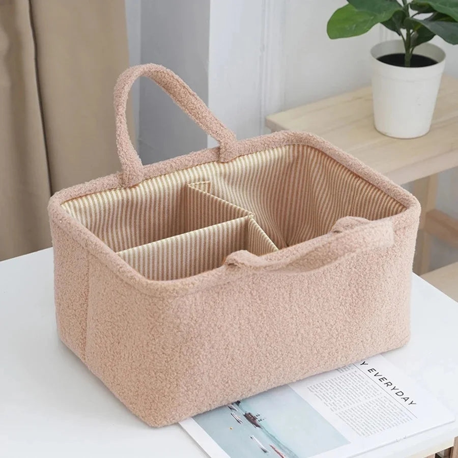 Sac organisateur multifonction beige pour bébé avec doublure rembourrée et tissu rayé, sur une table blanche.
