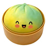 A yellow and green squishy dumpling stress relief toy shaped like a cute face in a round container.
