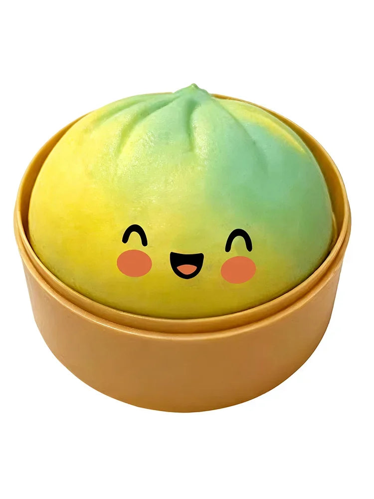 A yellow and green squishy dumpling stress relief toy shaped like a cute face in a round container.