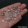 A hand holds a cluster of clear quartz round beads for jewelry making.