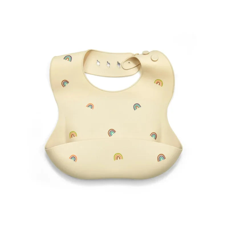 A beige soft silicone waterproof baby bib with an adjustable neck and rainbow accents.