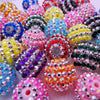 A close-up shot of mixed two-tone striped resin beads in various colors and finishes, including pink, purple, yellow, blue, a