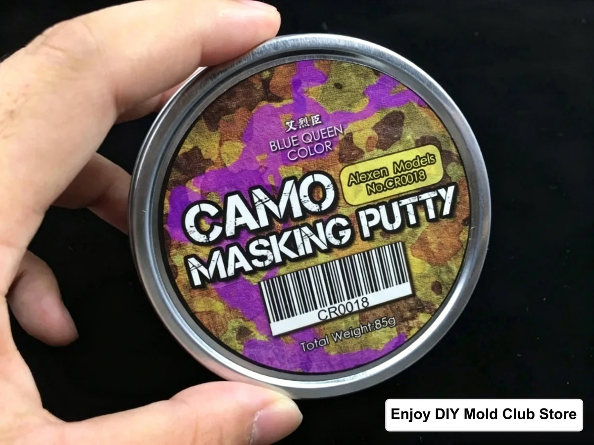 A hand holds a tin of Camo Masking Putty for model painting labeled Blue Queen Color.