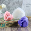 A collection of pink and purple 3D heart-shaped silicone molds for candles, soaps, and desserts displayed on a wooden box.