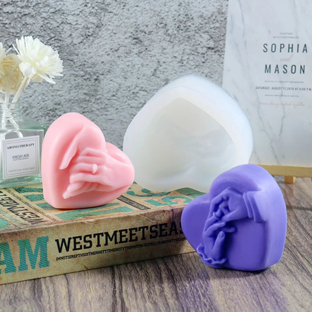 A collection of pink and purple 3D heart-shaped silicone molds for candles, soaps, and desserts displayed on a wooden box.