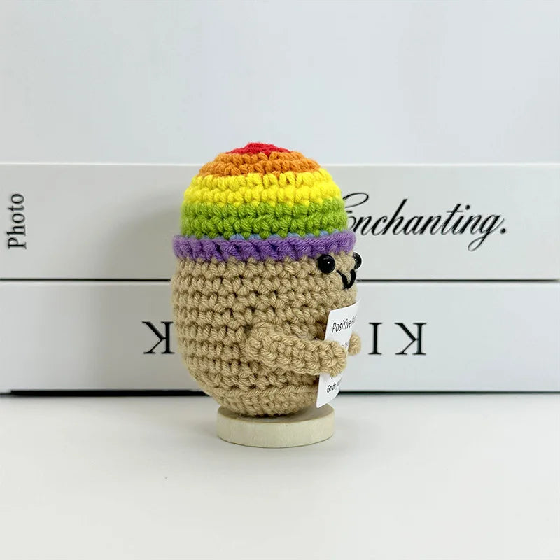 A handwoven crochet pencil ornament shaped like an elephant with multi-colored textured hair sitting on a white box.