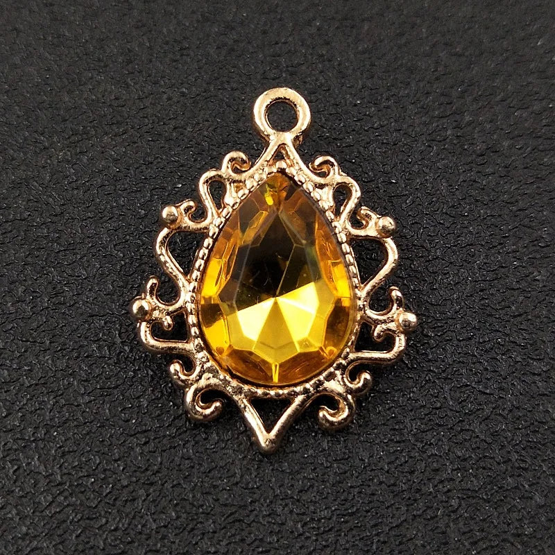 Gold plated water droplet charm featuring a faceted yellow crystal gemstone and an ornate flower setting.