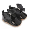 Black moccasin shoes for a baby girl featuring a black ribbon bow with silver lace trim